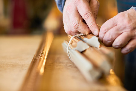 Man saving extra wooden picture frame moldings and binding with twine