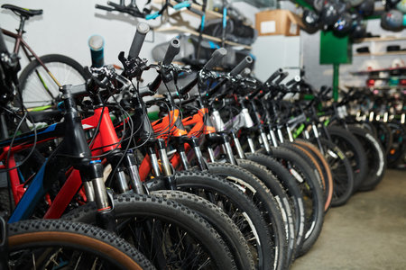 Row of mountain bikes standing in bike shop, handlebars and front wheels aligned closely, various...