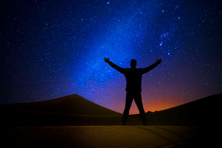 Man in front of the universe with his arms raisedの写真素材