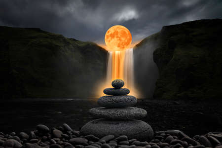 Zen stones balancing in front of waterfall and full moonの写真素材