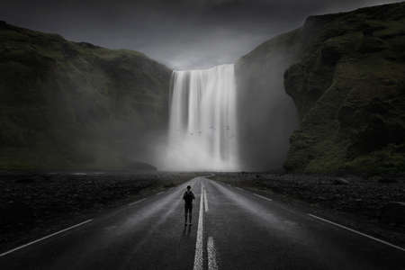 Backpacking on a surreal road heading towards a large waterfallの写真素材