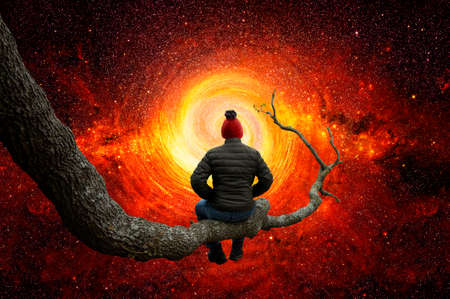 Man observes the space on the trunk of a large treeの写真素材