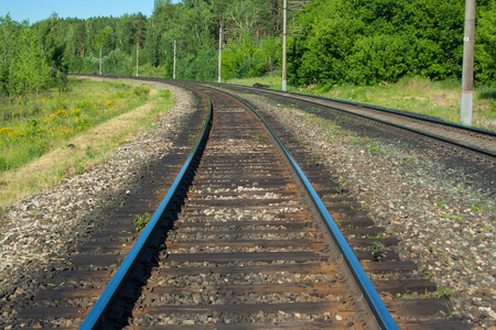 The railway goes into the distance on a sunny day with green trees and a riverの写真素材