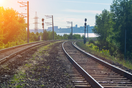 The railway goes into the distance on a sunny day with green trees and a riverの写真素材