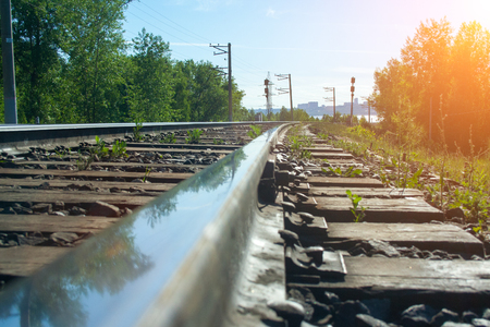 The railway goes into the distance on a sunny day with green trees and a riverの写真素材