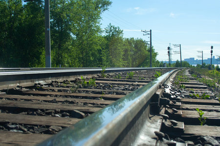 The railway goes into the distance on a sunny day with green trees and a river