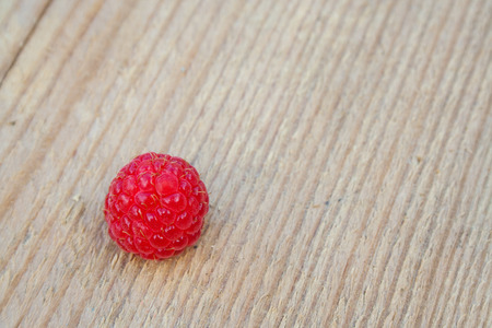Single red raspberry on the wooden table. Macroの写真素材