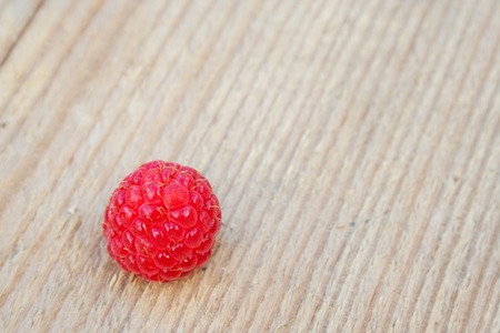 Single red raspberry on the wooden table. Macroの写真素材