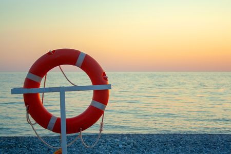 Orange life ring near sea on sunset. Saving life conceptの写真素材