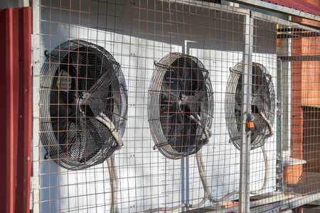 Several air conditioners outside the mall behind the bars are locked.の写真素材