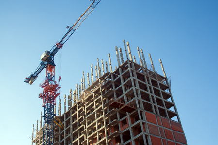 Construction crane in the process of building a new residential building. Construction of an apartment building bottom viewの写真素材