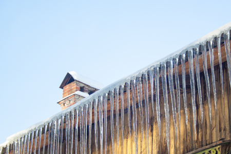 Hanging Icicles at wooden roof. Winter dangerous. Fall iciclesの写真素材