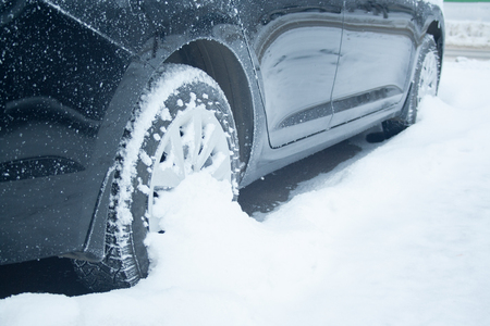 Wheel of black car at snow close up. Winter driving conceptの写真素材