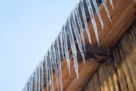 Hanging Icicles at wooden roof. Winter dangerous. Fall iciclesの写真素材