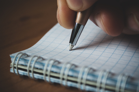 Pen and white notepad paper close up in man's handの写真素材
