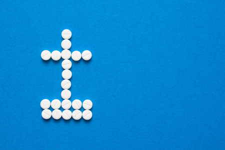 white pills in the shape of a grave cross are scattered on a blue background with copyspace. Depression, harm of drugs concepts. Top viewの写真素材