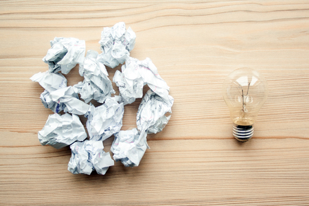 Heap of crumpled white paper balls with one light bulb against them. Concept of think different, think out of the box, leadership.  Illustration of baiting.の写真素材