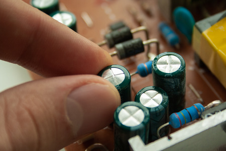 Broken bad old capacitor of computer screen with man's fingers. condenser breakdown. Monitor repairÑの写真素材