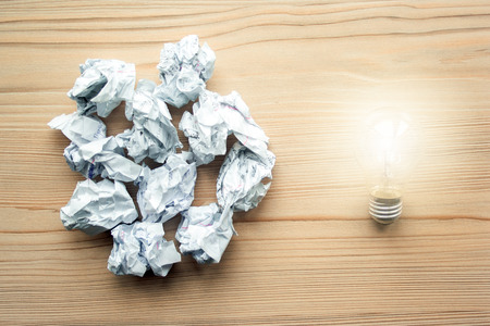 Heap of crumpled white paper balls with one light bulb against them. Concept of think different, think out of the box, leadership.  Illustration of baiting.の写真素材