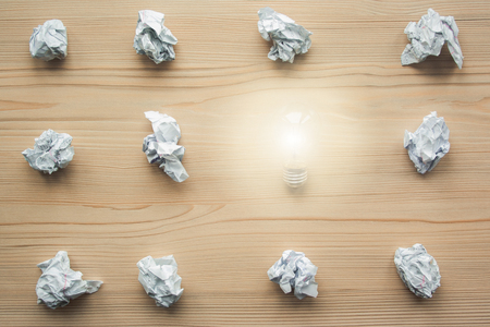 Many crumpled white paper balls with one light bulb between them. Concept of think different, think out of the box, leadership.の写真素材
