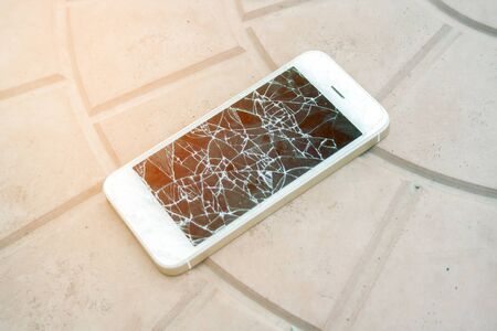 broken smartphone screen. Smartphone with a broken screen on the tile floor. Side view broken phone. negligenceの写真素材