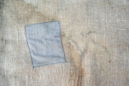 Aged vintage and weathered cloth background texture with patch. Old damaged brown rough texture の写真素材
