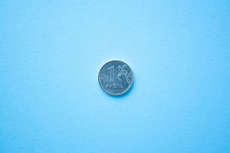 Coin one rouble on bright blue background. ruble depreciation. Rouble to dollar