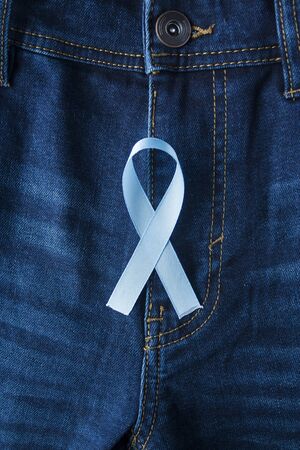 Prostate Cancer Awareness, light Blue Ribbon on male jeans fly background. Closeup, hope, cure, treatment, medical symbol. Blue ribbon on men crotch verticalの写真素材