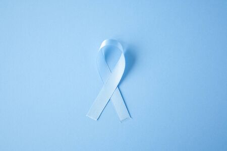 Prostate cancer awareness blue ribbon on blue background. Men healthcare concept, men carcinoma symbol.の写真素材