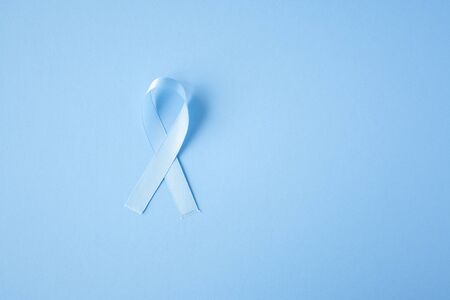 Prostate cancer awareness blue ribbon on blue background. Men healthcare concept, men carcinoma symbol.の写真素材