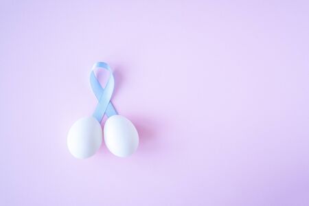 prostate cancer, healthcare, profession, medicine concept - close up of chicken white eggs and blue ribbon in penis shape on bright background. Cancer awareness, cure, men carcinomaの写真素材