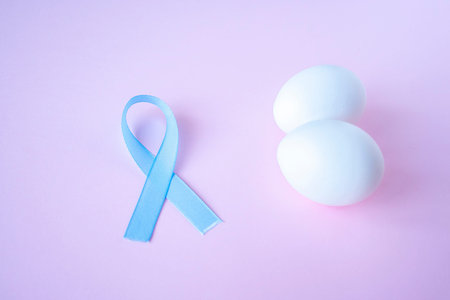 prostate cancer, healthcare, profession, medicine concept - close up of chicken white eggs and blue ribbon on bright background. Cancer awareness, cure, men carcinomaの写真素材
