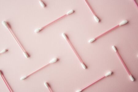 Flat lay cotton buds on pink warm background. Pattern of cotton swubs, beauty and health care concept. Cotton compositionの写真素材