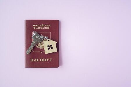 Russian international Passport and key  with trinket house on it on pink background close up copy space. Immigration, emigration, citizenship conceptの写真素材