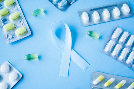 Blue ribbon symbol of prostate cancer with many pills and drugs clusters on bright background....