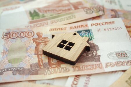 Mortgage, insurance, buying and rent, real estate business concept. Small wooden house toy on money rouble banknotes background side viewの写真素材