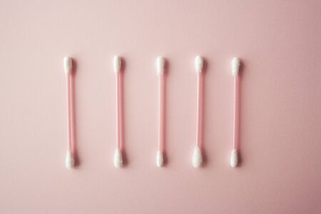 Flat lay cotton buds on pink warm background. Row of cotton swubs, beauty and health care concept. Cotton compositionの写真素材