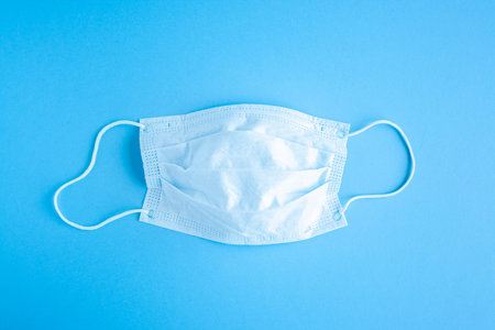 Disposable medical mask on blue backggroun against bacteria and viruses. Stop the spread of...