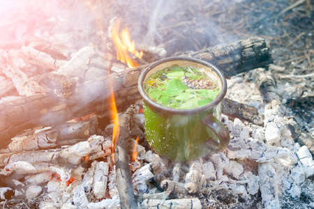 Cup of tea in the bonfire flames. Cooking food at fire in wild.の写真素材