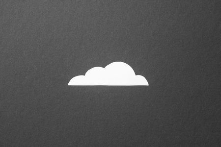 White cut out paper cloud on black background