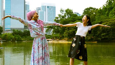 Feeling alive in the outdoors! Two women hold hands and embrace the momentの写真素材
