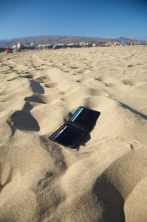 lost black leather wallet with four cards at the beachの写真素材
