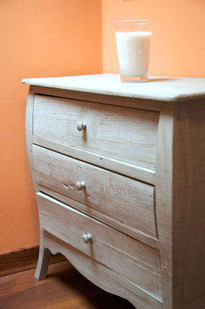 detail of old furniture with a candle glass on orange wall