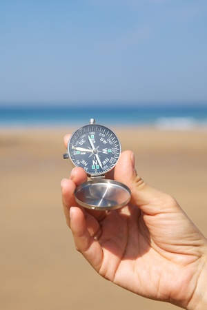woman hand with a black and silver compass in a beachの写真素材