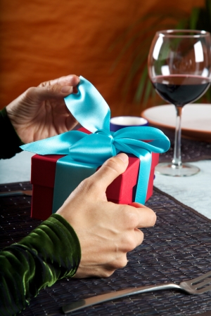 woman at restaurant opening a blue bow gift packageの写真素材