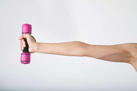 woman arm at gym lifting dumbbells over white backgroundの写真素材