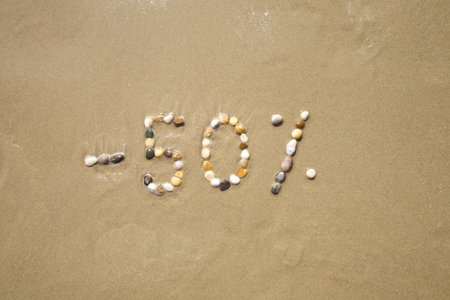 fifty percent discount word writing with small stones on sand beach groundの写真素材