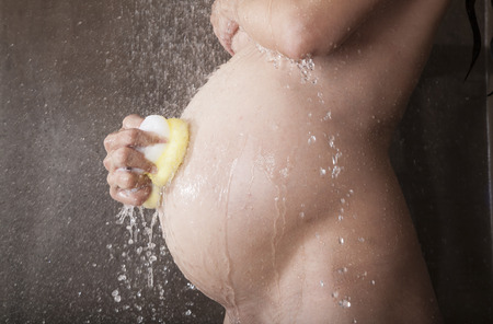 pregnant woman with white bikini under shower waterの写真素材