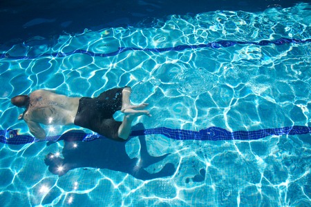 man with swimsuit swimming on a blue water poolの写真素材