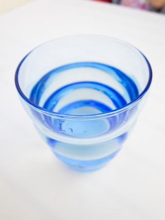 macro of blue glass with water on white tableclothの写真素材